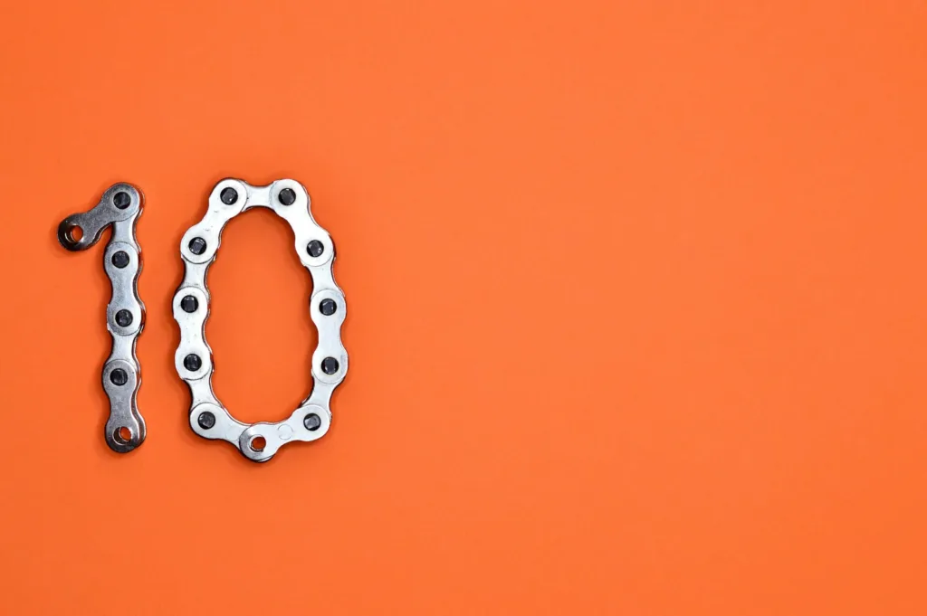 Number ten formed from a silver bike chain on an orange background, representing the Ten Essential Lending Tools to transform your business in 2025.