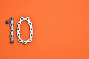 Number ten formed from a silver bike chain on an orange background, representing the Ten Essential Lending Tools to transform your business in 2025.