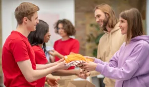 Volunteers handing folded clothes to people at a donation center.