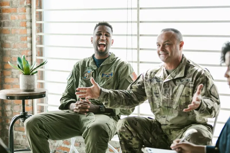Military servicemembers smiling during a discussion, highlighting awareness of SCRA military benefits and protections.