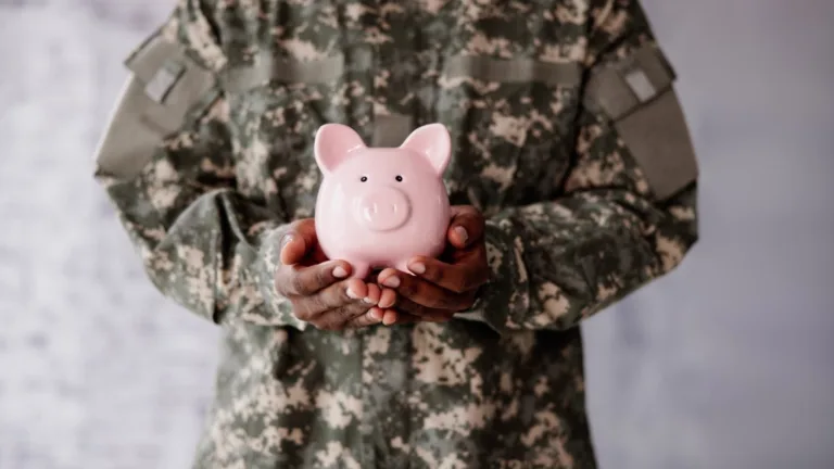 Servicemember in uniform holding piggy bank, symbolizing financial protections from SCRA military benefits.