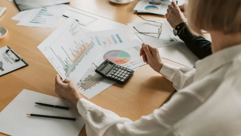 A team reviewing printed reports at a wooden desk.