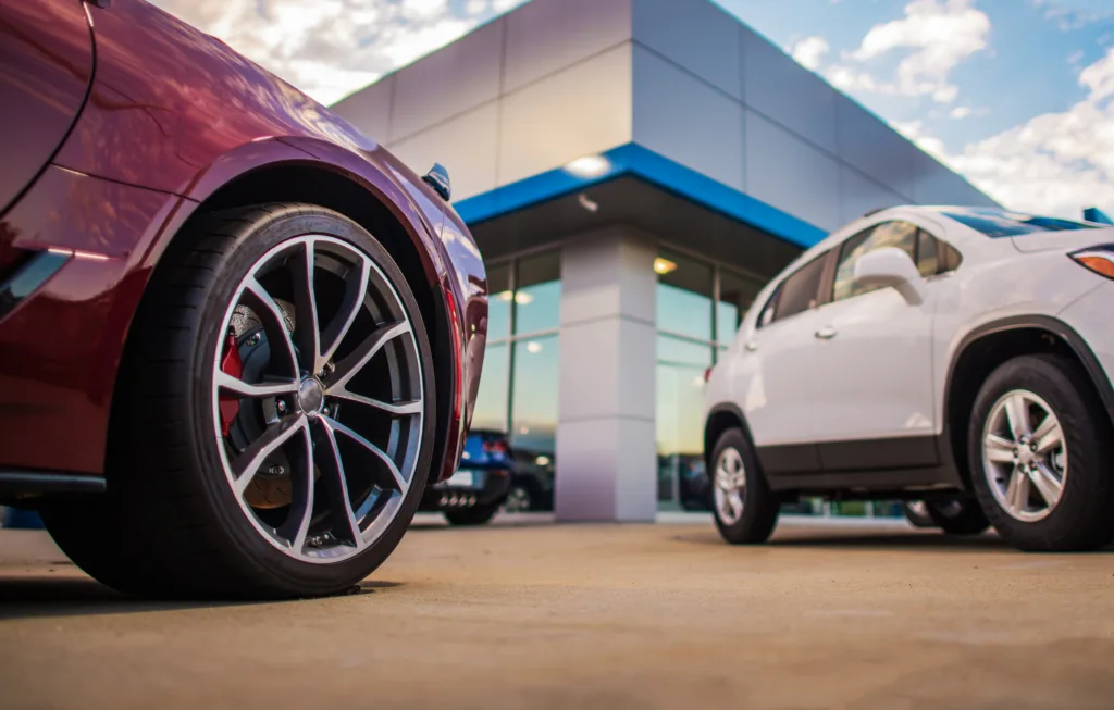 Vehicles parked outside an automotive dealership, representing auto financing and lending compliance.