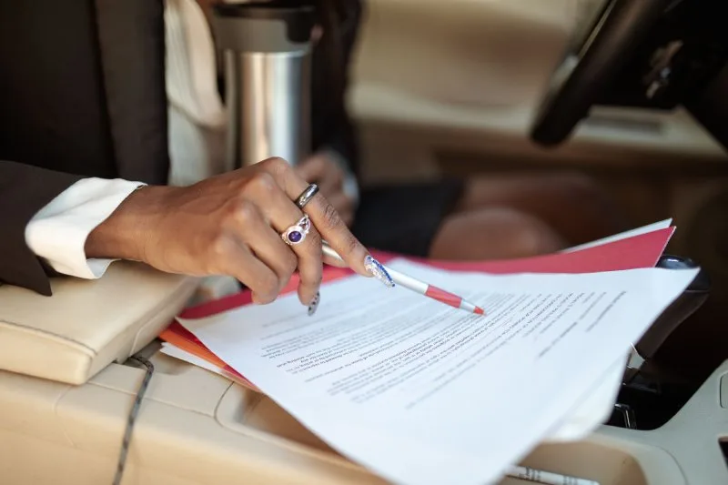 Borrower reviewing indirect auto loan documents inside a vehicle at a dealership
