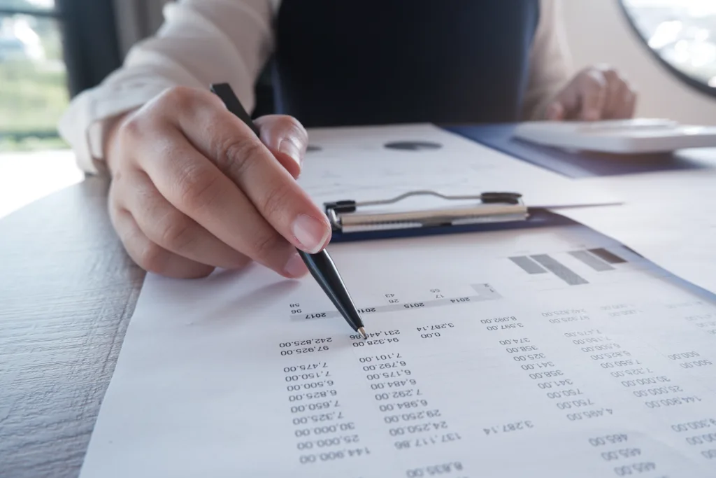 Businesswoman reviewing financial data and loan documents at her desk.