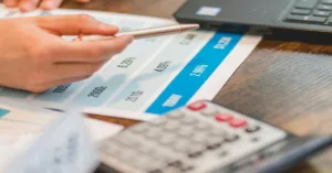 Hand pointing at an interest chart representing the rule of 78 beside a calculator.