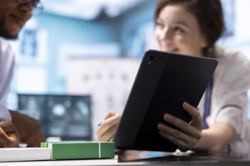 Two lending professionals reviewing loan servicing software options together on a tablet 