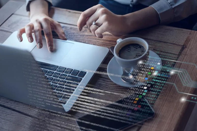 Woman using laptop with code overlay representing software selection.