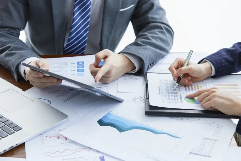 Lending team reviewing portfolio performance charts and loan reports on tablet and paper 