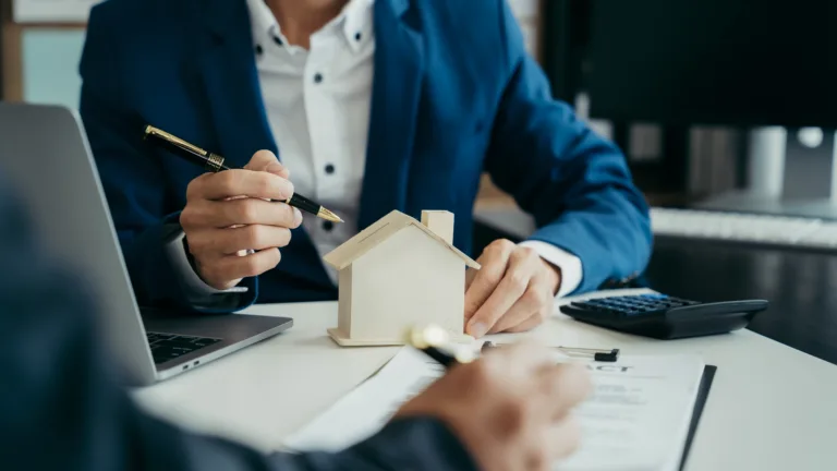 Financial professional explaining reverse mortgage terms with a home model and loan documents.