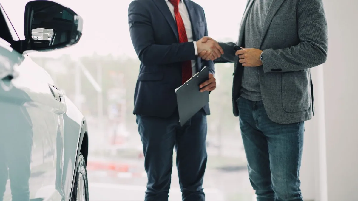 Auto dealer and borrower shaking hands after securing indirect auto financing at a dealership