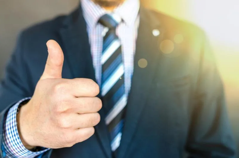 Businessman in suit giving thumbs up, symbolizing successful credit tracking.