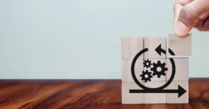 Wooden blocks showing circular workflow with gears representing the loan lifecycle process from origination through servicing