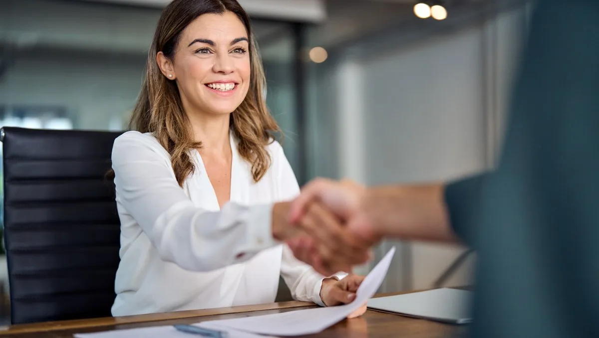 Loan servicing professional shaking hands with a borrower after signing loan paperwork.
