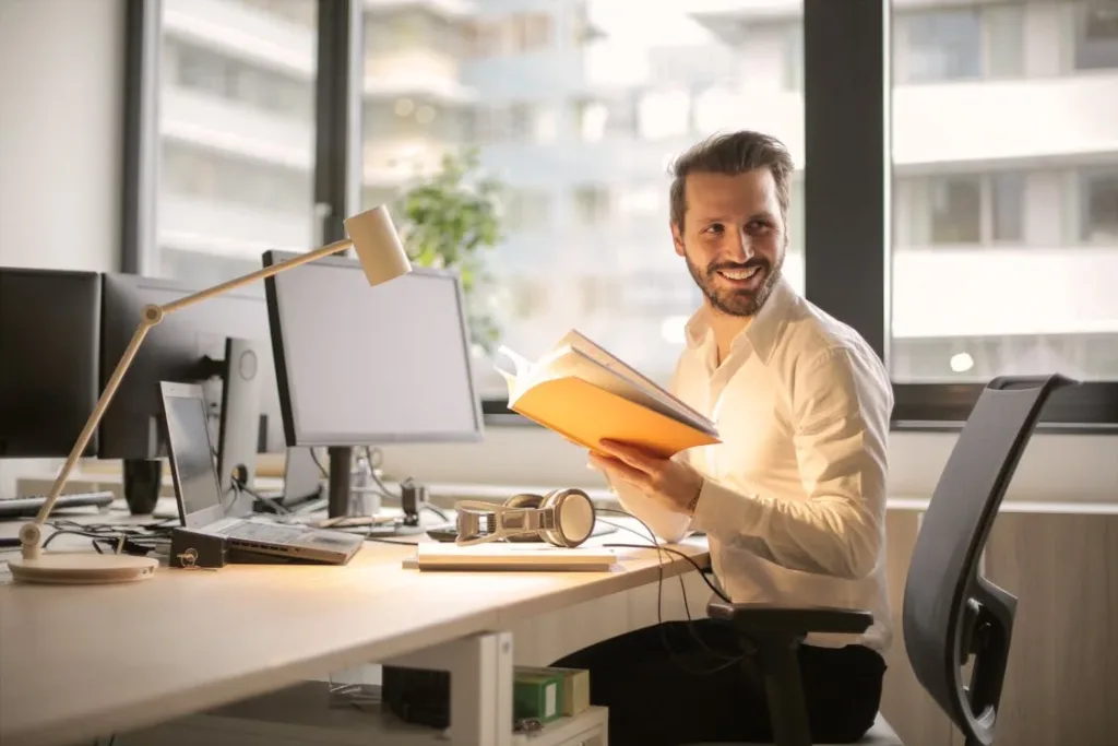man at computer reading a book