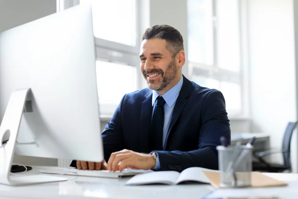 Smiling loan servicing professional working at a computer in a bright office.