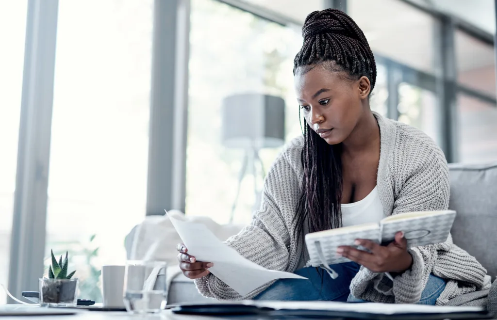 Female student reviewing paperwork and notes at home.