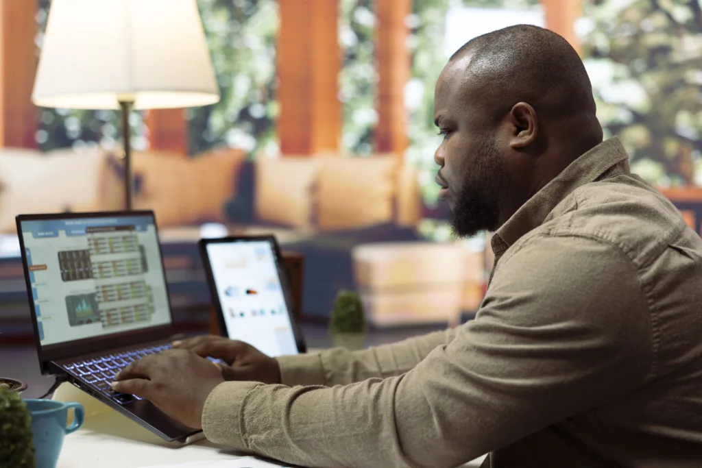 Loan servicer analyzing portfolio data on dual monitors with reporting dashboards