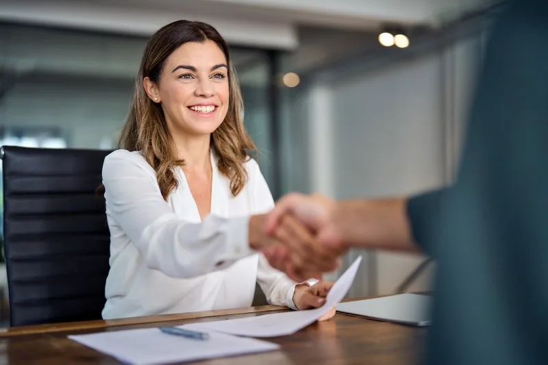 Loan servicing professional shaking hands with a borrower after a successful lending relationship meeting. 