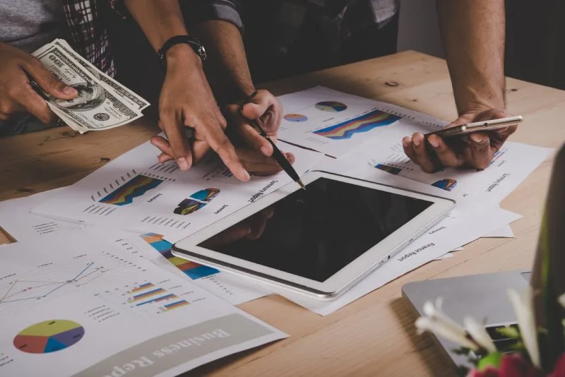 Loan servicers reviewing portfolio performance reports and financial data to manage loan delinquency. 