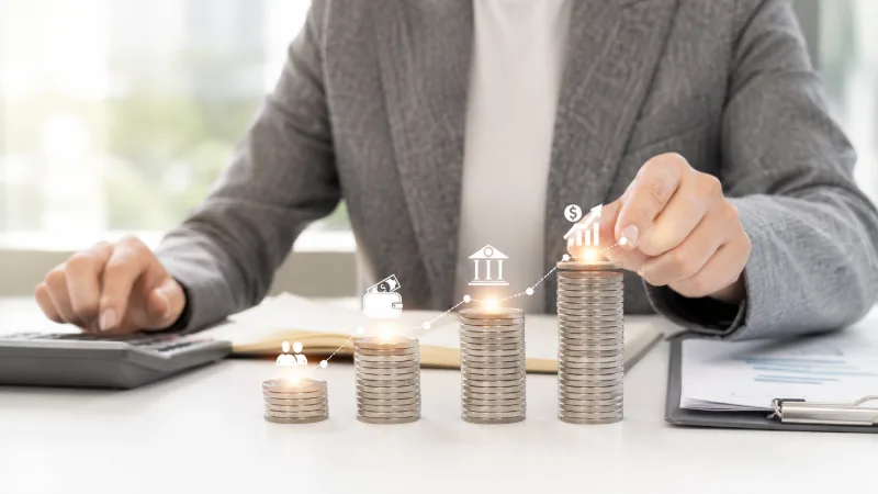 Stacked coins with rising chart icons representing loan profitability growth for lenders. AI-generated. 